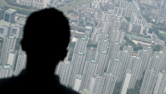 한 시민이 서울 송파구 롯데월드타워 서울 스카이 전망대에서 아파트 밀집 지역을 바라보고 있다.<연합뉴스>